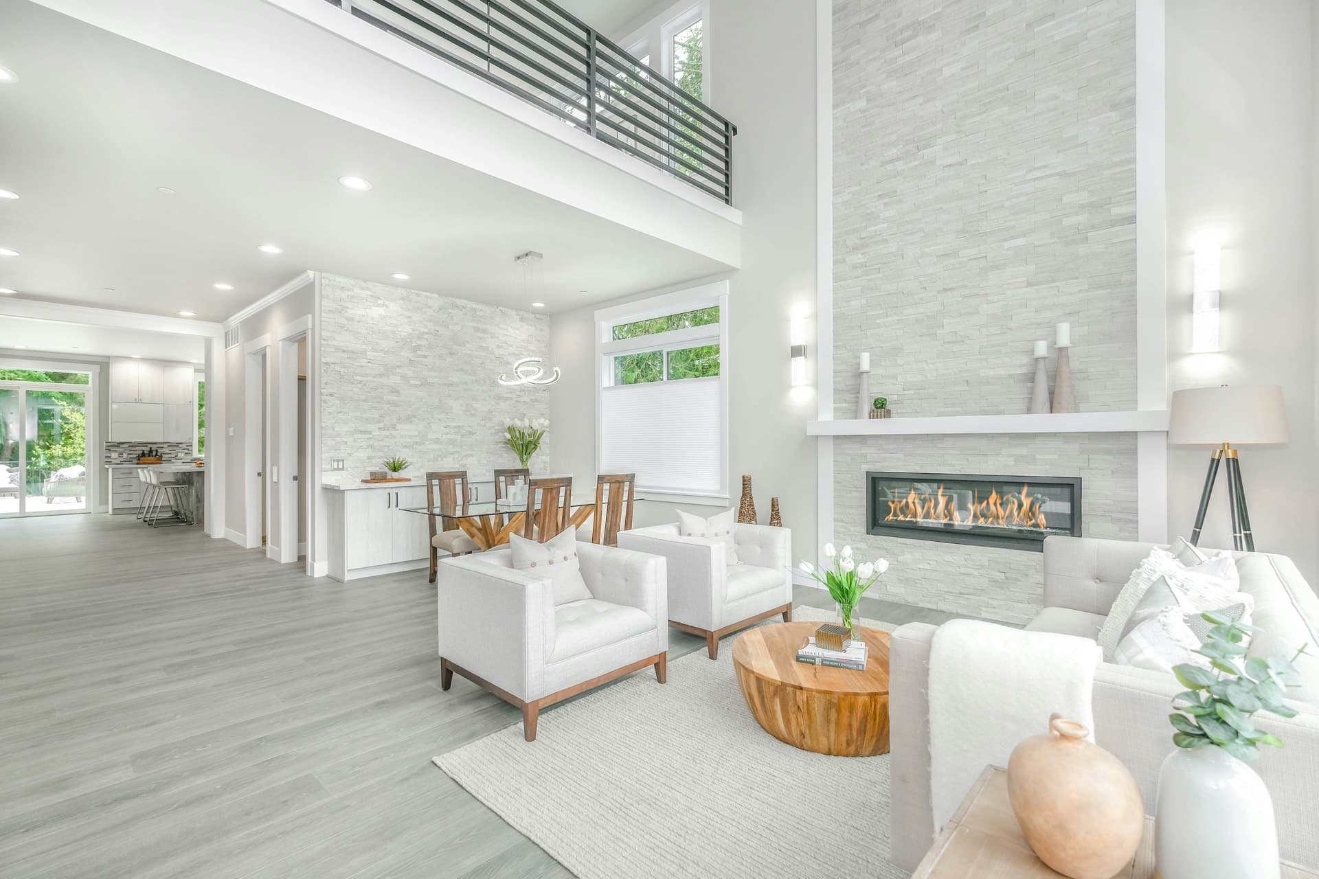 Contemporary living room with double-height ceiling, stone fireplace, and natural wood accents